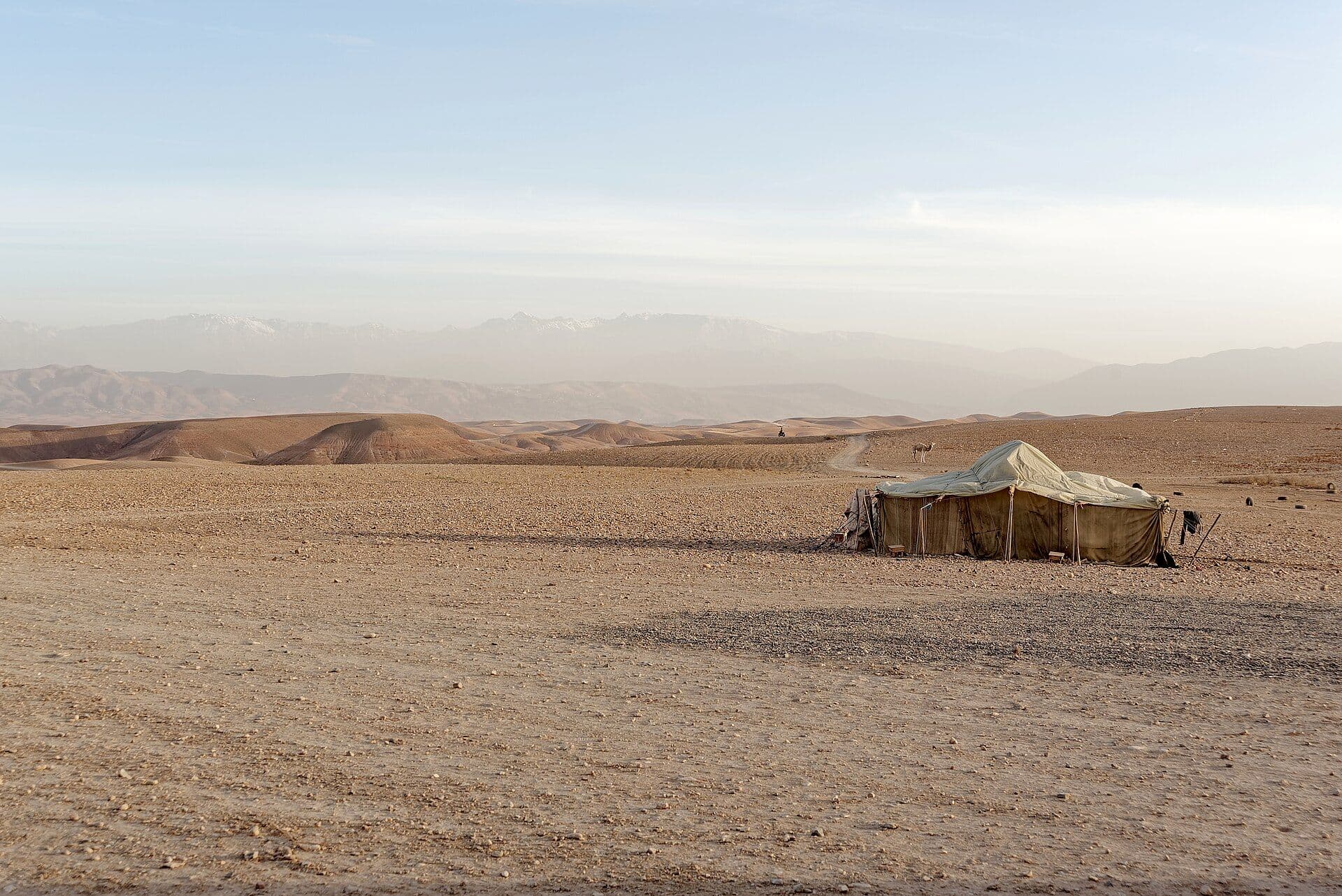 Berber tent in the stony landscape of the Agafay desert with the Atlas in the background