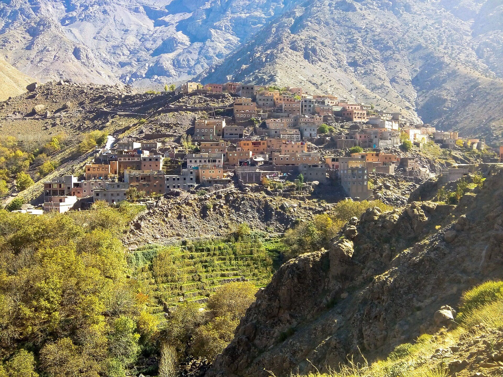 A Berber village of mud-brick houses on a slope, with the snow-capped peaks of the High Atlas behind it