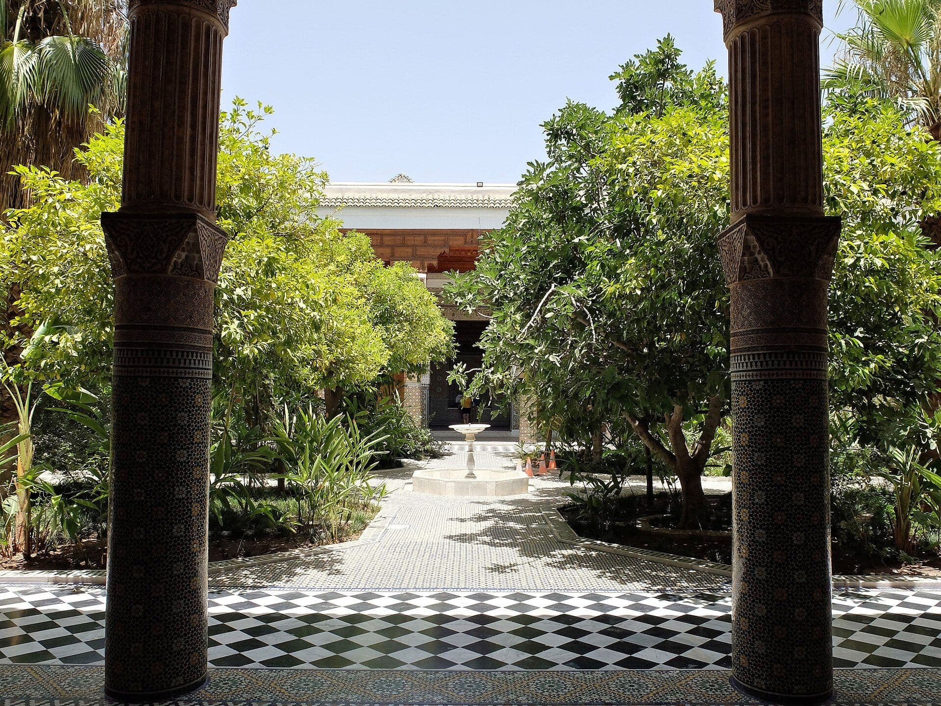 Shady courtyard garden of a riad in Marrakesh with orange trees and black and white tiles