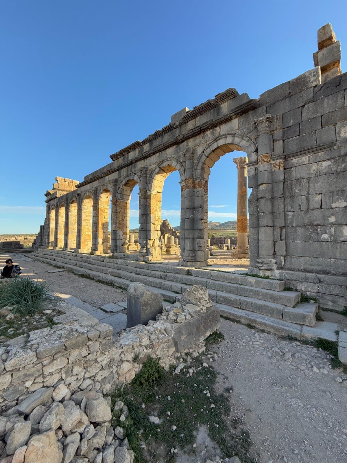 A row of Roman arches and columns in Volubilis under a blue sky